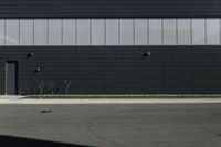 black street light on the side of a dark building with white siding and brick wall