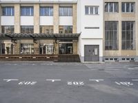 an empty building with signs on the street and people on bikes in traffic passing by