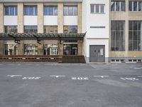 an empty building with signs on the street and people on bikes in traffic passing by