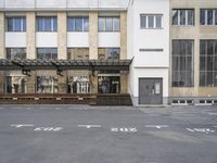 an empty building with signs on the street and people on bikes in traffic passing by