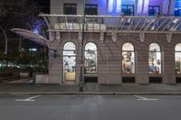 the corner of an empty building has windows lit with brightly lit lights on it's side