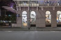 the corner of an empty building has windows lit with brightly lit lights on it's side