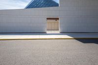 a closed door in the white building on a street corner with pavement and yellow curb