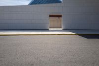 a closed door in the white building on a street corner with pavement and yellow curb