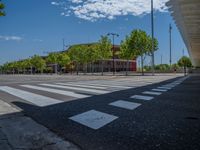 a car sitting at an empty street underneath a overpass overhang that contains a train stop, and cars and a pedestrian