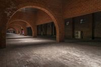 a brick walkway is seen between two archways to create an open space for a couple of people