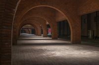 a brick walkway is seen between two archways to create an open space for a couple of people