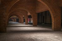 a brick walkway is seen between two archways to create an open space for a couple of people