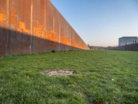 this grass field has been cut short to cover the area in the distance, and it is a grassy area next to an old building