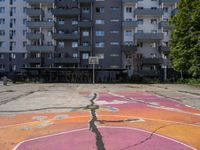 an empty basketball court with painted markings on it's floor and building behind it