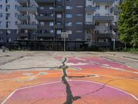 an empty basketball court with painted markings on it's floor and building behind it