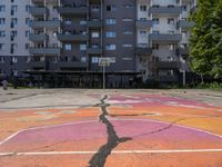 an empty basketball court with painted markings on it's floor and building behind it