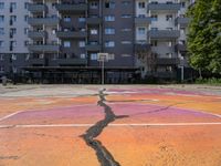 an empty basketball court with painted markings on it's floor and building behind it