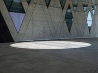 a shadow is seen on the pavement in front of a building with windows and triangles