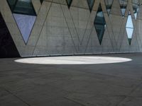 a shadow is seen on the pavement in front of a building with windows and triangles