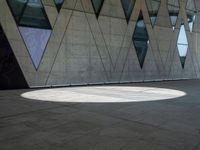 a shadow is seen on the pavement in front of a building with windows and triangles