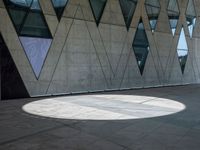 a shadow is seen on the pavement in front of a building with windows and triangles