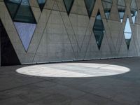 a shadow is seen on the pavement in front of a building with windows and triangles