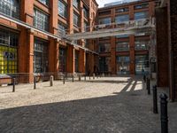 the buildings are in one block of bricked walkway with an overhead walkway on one side, surrounded by a metal fence