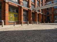 the buildings are in one block of bricked walkway with an overhead walkway on one side, surrounded by a metal fence