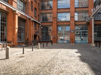 the buildings are in one block of bricked walkway with an overhead walkway on one side, surrounded by a metal fence