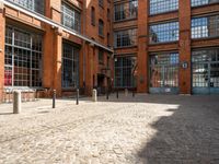 the buildings are in one block of bricked walkway with an overhead walkway on one side, surrounded by a metal fence