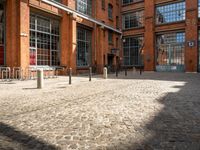 the buildings are in one block of bricked walkway with an overhead walkway on one side, surrounded by a metal fence