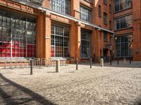 the buildings are in one block of bricked walkway with an overhead walkway on one side, surrounded by a metal fence