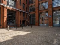 the buildings are in one block of bricked walkway with an overhead walkway on one side, surrounded by a metal fence