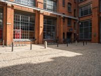 the buildings are in one block of bricked walkway with an overhead walkway on one side, surrounded by a metal fence