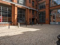 the buildings are in one block of bricked walkway with an overhead walkway on one side, surrounded by a metal fence