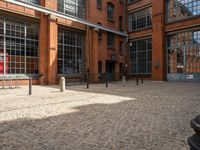 the buildings are in one block of bricked walkway with an overhead walkway on one side, surrounded by a metal fence