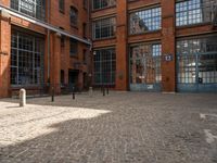 the buildings are in one block of bricked walkway with an overhead walkway on one side, surrounded by a metal fence