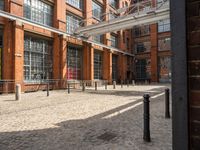 the buildings are in one block of bricked walkway with an overhead walkway on one side, surrounded by a metal fence