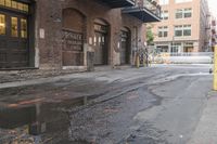 a reflection of the building is in puddles of water as a yellow fire hydrant sits beside it