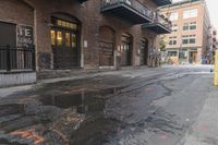 a reflection of the building is in puddles of water as a yellow fire hydrant sits beside it