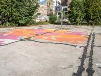 a basketball court painted with an orange and pink butterfly on it in the parking lot