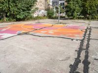 a basketball court painted with an orange and pink butterfly on it in the parking lot