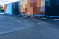 a blue and orange wall with colorful squares on it in the parking lot of a building