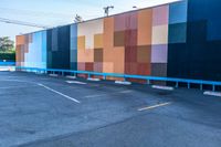 a blue and orange wall with colorful squares on it in the parking lot of a building