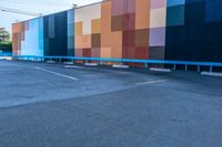 a blue and orange wall with colorful squares on it in the parking lot of a building