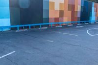 a blue and orange wall with colorful squares on it in the parking lot of a building