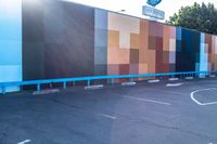 a blue and orange wall with colorful squares on it in the parking lot of a building