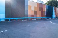 a blue and orange wall with colorful squares on it in the parking lot of a building