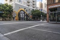 some street lights cars buildings and a large mural on the wall of a building in san francisco, california