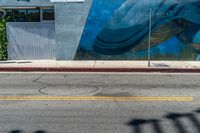 a mural painted on the side of a wall with a blue whale in front of a store