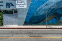 a mural painted on the side of a wall with a blue whale in front of a store