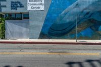 a mural painted on the side of a wall with a blue whale in front of a store