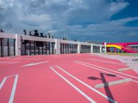 a basketball court with many colored lines in front of a building with two ladders