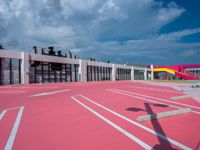 a basketball court with many colored lines in front of a building with two ladders